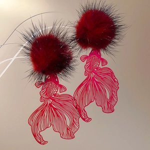 Detail of red pom-pom earrings with intricate gold hollow koi fish charm pendants