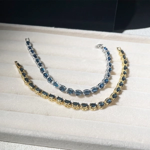 Detail of gold and silver tennis bracelets with oval dark blue zircon stones on velvet
