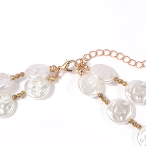 Double-layered gold necklace featuring irregular white pearls and polished beads