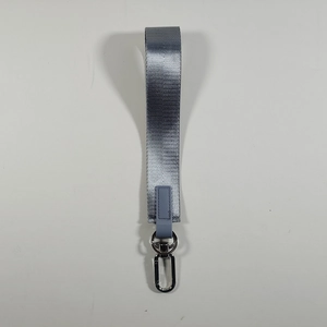 Dettaglio del cinturino portachiavi grigio intrecciato con moschettone argento e pelle