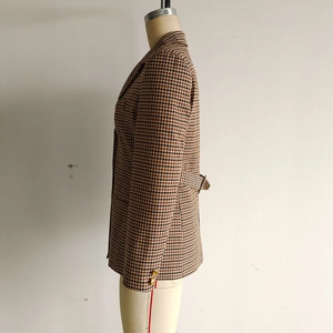 Close-up of houndstooth plaid blazer featuring gold buttons and waist buckle detail