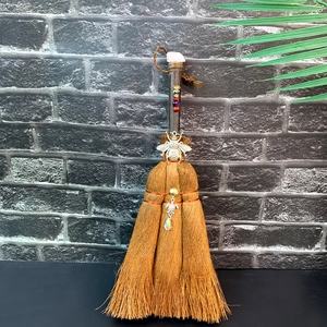 Detail of brown witch broom featuring a pink crystal, silver bee charm and colorful beads