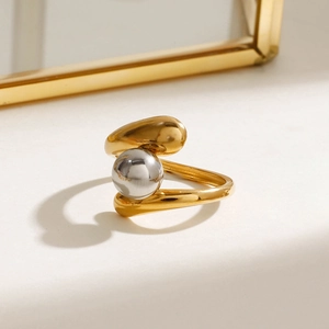 Modern two-tone stainless steel open ring with silver bead accent on a minimalist white surface