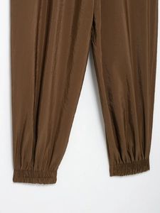 Detail of loose fit dark brown safari pants showing the elastic cuffs and nylon fabric texture