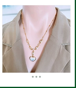 Close-up of gold heart pendant necklace with rectangular crystal chain on neck