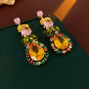Macro shot of leaf-shaped gold stud earrings with colorful teardrop zircon crystals