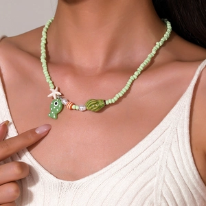 Dettaglio di una collana di perline con elementi marini, pesce e stella marina indossata