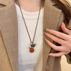 Detail of red square stone pendant with woven cord and vintage beads on model