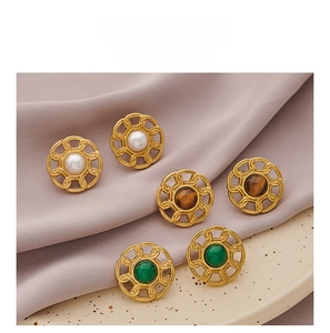 Detailed close-up of retro gold earrings set with pearls and natural stones on silk