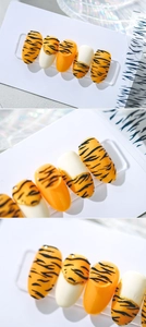Macro detail of 5D embossed tiger print nail stickers with orange and gold accents