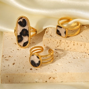 Drei goldene Ringe mit Leopardenmuster auf Stein und Seide in Nahaufnahme