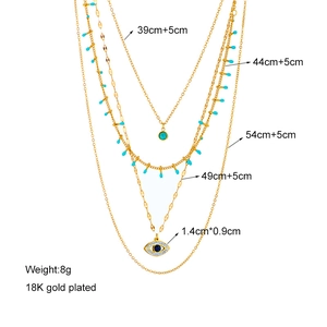 Detail of 18K gold plated layered chain necklace with turquoise and evil eye pendant