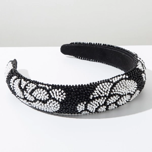 Détail de perles faites à la main avec motifs floraux blancs sur un bandeau noir large