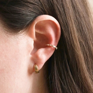 Orecchino a cerchio dorato con strisce e ear cuff con zircone indossato da una modella