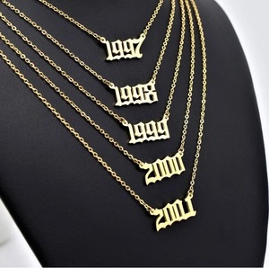 Détail de pendentifs année en acier inoxydable doré 18K superposés de 1997 à 2001 sur mannequin
