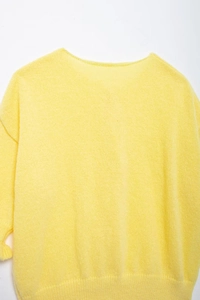 Close-up of bright yellow knit cardigan texture featuring soft fluffy mohair-style fibers