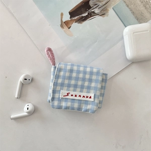 Detalle de funda de tela a cuadros azules para auriculares con cordón rosa y solapa