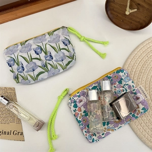 Detail of floral makeup bags with colorful ropes and zippers on a textured background
