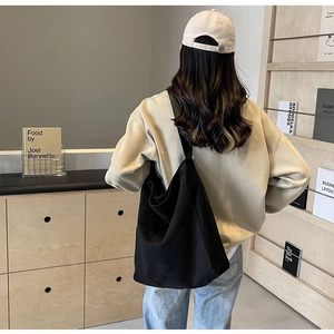 Detailansicht der schwarzen übergroßen Tragetasche an einem Model in einem minimalistischen Raum