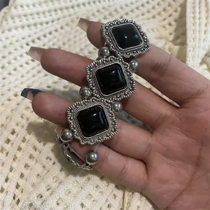 Détail d'un bracelet vintage en perles de métal argenté avec trois pierres en résine noire