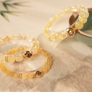 Close-up of citrine beaded bracelets with gold spacers on a traditional landscape background