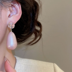 Close-up of elegant pink teardrop pearl earrings with crystals worn by a model