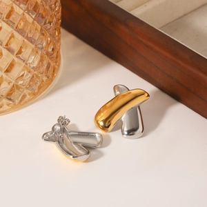 Two-tone X-shaped stainless steel earrings in gold and silver on a minimalist setup