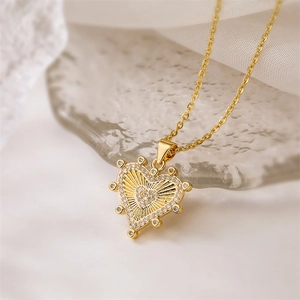 Close-up of gold heart pendant with cubic zirconia on elegant white fabric