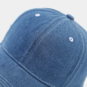 Macro view of denim baseball cap crown with white contrast stitching and eyelets