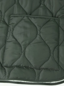 Detail of army green quilted jacket featuring wavy stitching and a large square pocket