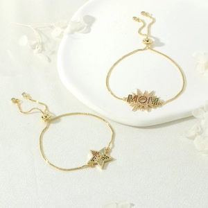 Elegant gold MAMA bolo bracelet with rainbow zircon stars on white silk background
