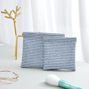 Detail of blue and white woven cosmetic bag with automatic metal squeeze closure