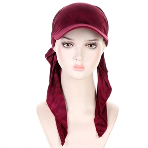 Detailed view of burgundy velvet turban hat with brim and ties on professional model