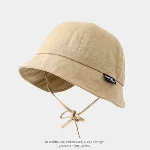 Detail of beige cotton baby sun hat featuring adjustable chin strap and fabric brand label
