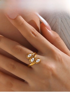 Close-up of gold plated ring featuring three oval pearls in a cluster on finger