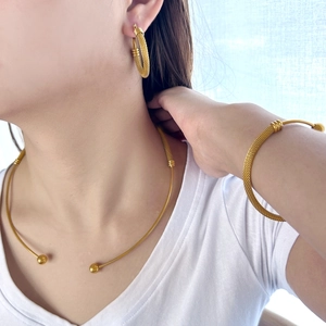 Detailed view of golden mesh texture necklace and earrings set on a female model