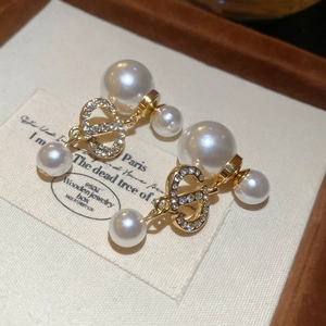 Close-up of gold plated pearl earrings featuring crystal CD logo in a wooden box