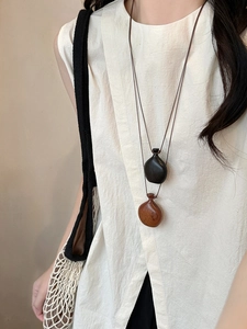 Detailed view of wood gourd pendants in black and brown on a long drawstring necklace