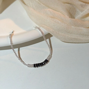 Detail of silver chain bracelet with embedded white zircons and black rectangular stones