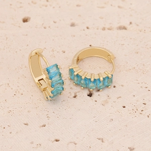 Gold plated hoop earrings featuring square sky blue cubic zirconia on a stone surface