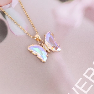 Detailed close-up of a golden butterfly pendant with iridescent wings and fine chain