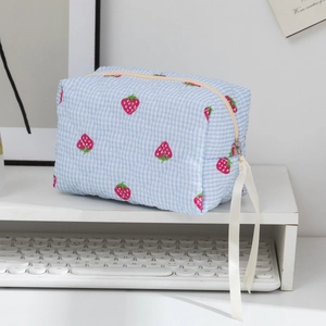 Détail de la trousse à maquillage à carreaux et fraises avec ruban sur la fermeture