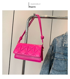 Detail of rose red rectangular shoulder bag featuring 3D triangle quilting and knotted strap