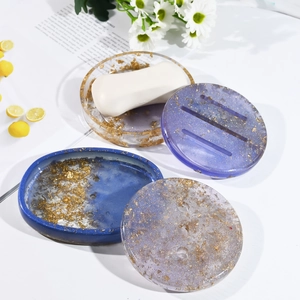 Detailed view of DIY resin soap dish molds featuring gold foil and glitter in oval shapes