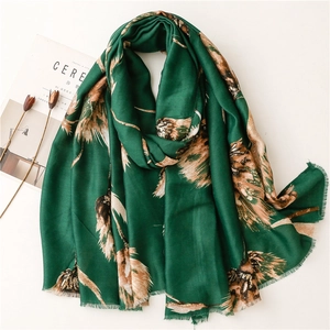 Close-up of green cotton-linen scarf with gold foil leaf patterns and fringed edges