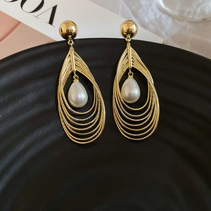 Nahaufnahme mehrlagiger goldener Tropfenohrringe mit einer eleganten weißen Perle in der Mitte