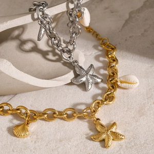 Minimalist 18k gold starfish and shell charm bracelet with thick chain on stone texture