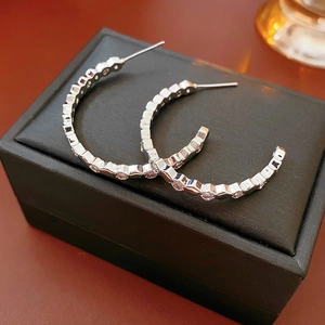 Détail macro de boucles d'oreilles argentées en C avec zircons carrés sur écrin noir
