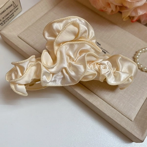 Detail of cream satin hair claw clip with elegant silk texture on a decorative tray