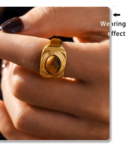 Close-up of gold titanium steel ring with oval tiger eye stone on model's finger